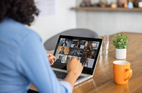 Une femme assise à une table, participant à une conférence téléphonique en ligne sur son ordinateur.