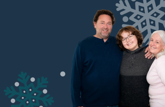 Une famille de trois personnes (mère, père et fils) s'embrassant et souriant. De gros flocons de neige sont en arrière-plan