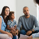 Une famille de 3 personnes (père, mère et fils) se faisant annoncer une nouvelle par une personne hors de vue.